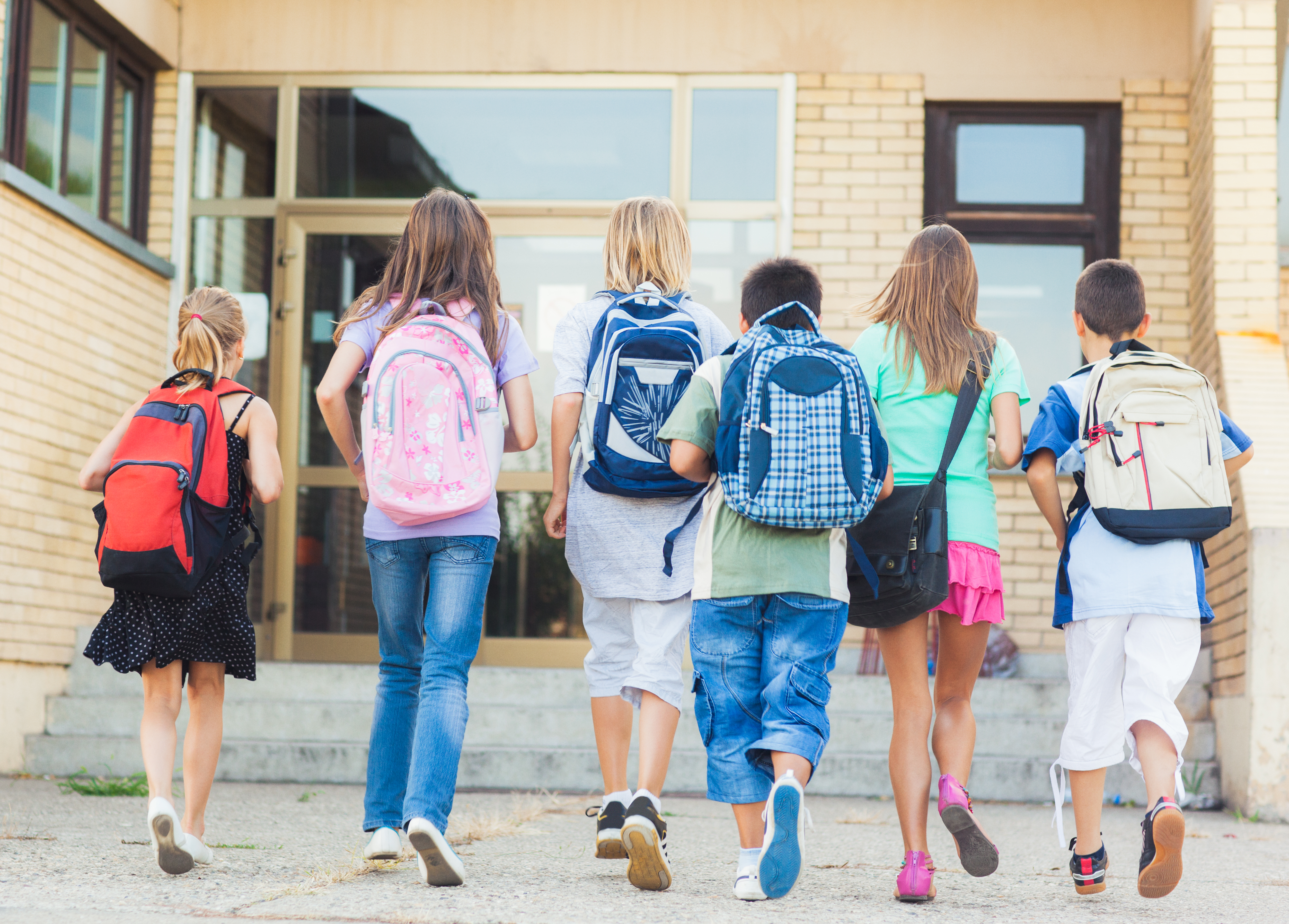 Group of kids with backpacks walking into school