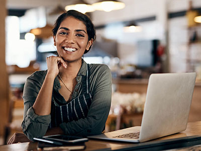 Woman business owner with open laptop smiling at the camera