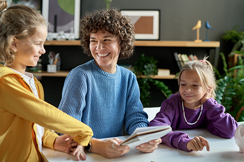 White adult woman sitting with her two daughters a the kitchen table