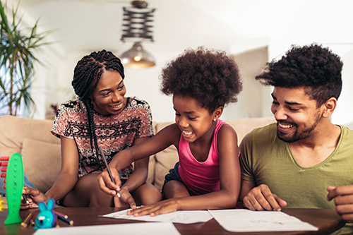 Black man and woman with daughter sitting on a couch and looking a pieces of paper