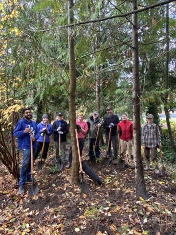 7 volunteers holding shovels in a park after a planting event